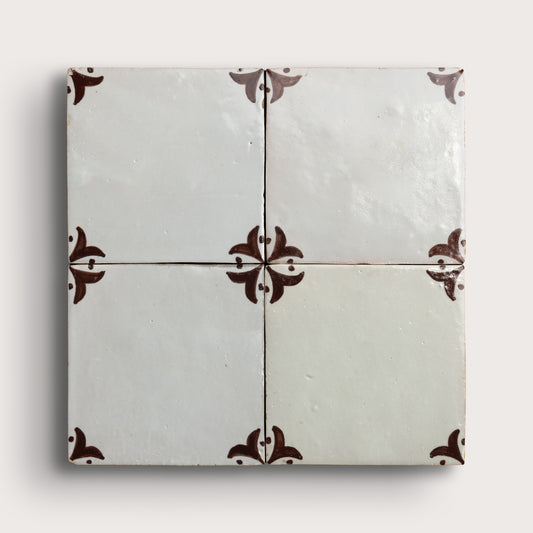 square zellige tile in a grid format with brown handpainted fleur pattern.