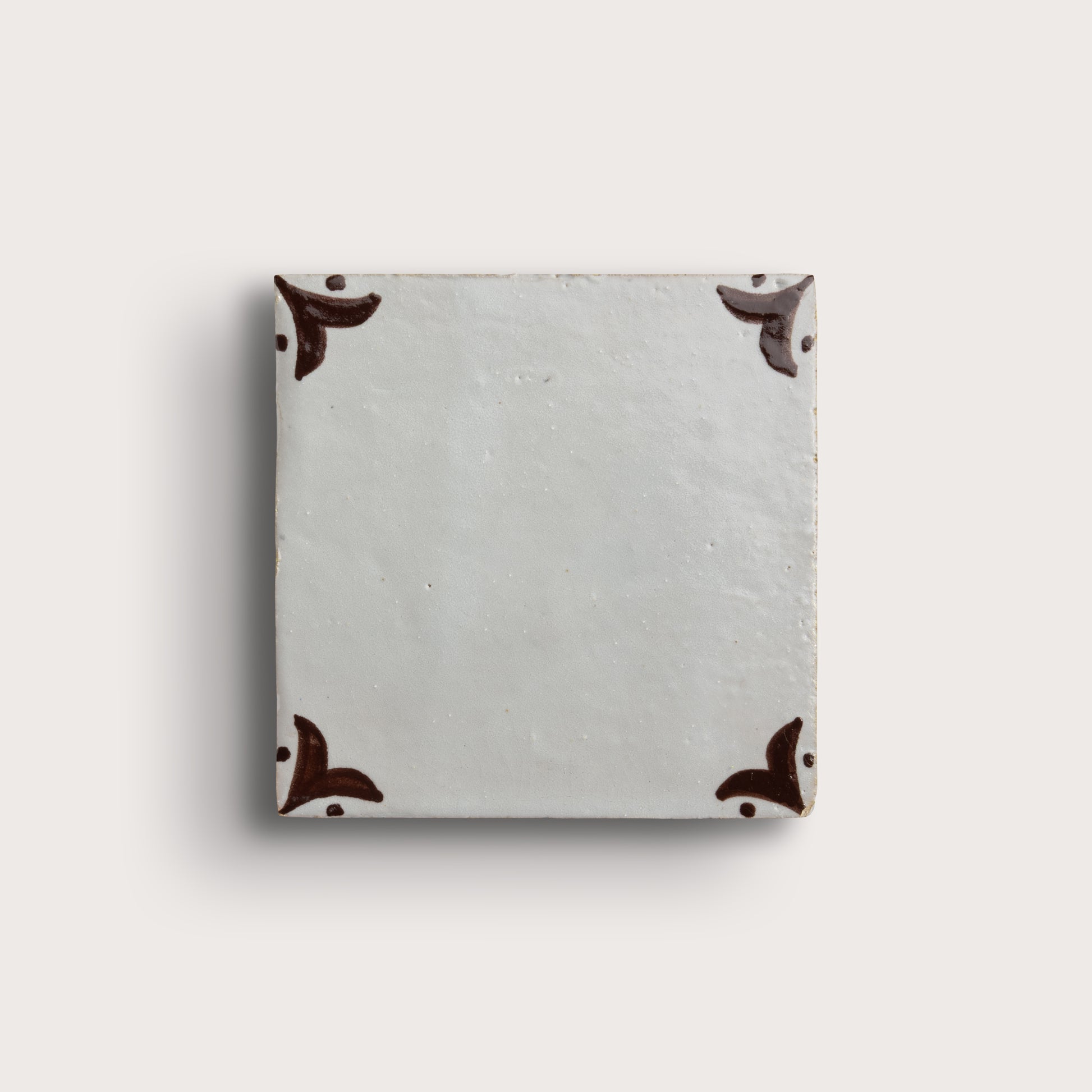 square zellige tile in a grid format with brown handpainted fleur pattern.