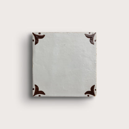 square zellige tile in a grid format with brown handpainted fleur pattern.