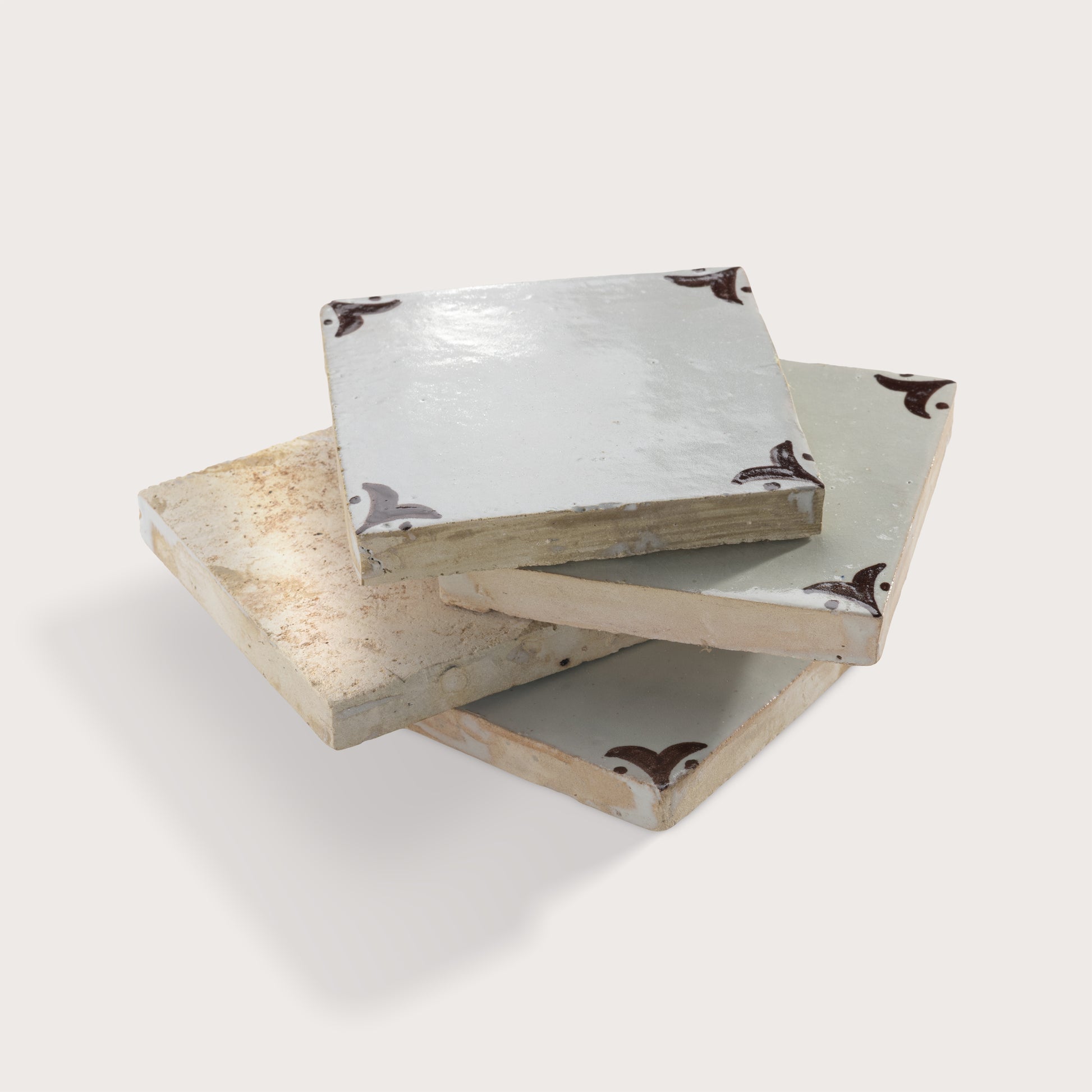 square zellige tile stacked with brown handpainted fleur pattern.