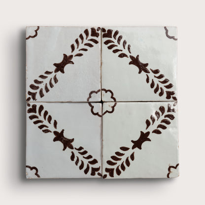 Four square zellige tiles arranged in a 2x2 grid, featuring a glossy off-white glaze with a dark brown hand-painted botanical pattern of leafy stems and star-like motifs.