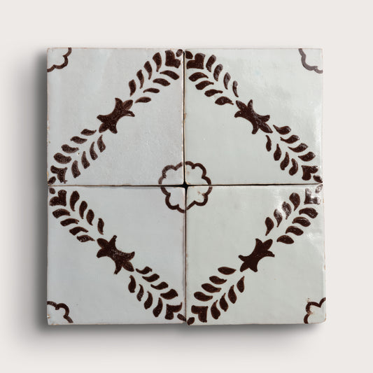 Four square zellige tiles arranged in a 2x2 grid, featuring a glossy off-white glaze with a dark brown hand-painted botanical pattern of leafy stems and star-like motifs.
