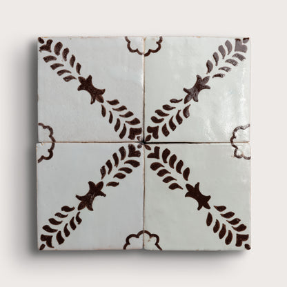 Four square zellige tiles arranged in a 2x2 grid, featuring a glossy off-white glaze with a dark brown hand-painted botanical pattern of leafy stems and star-like motifs.