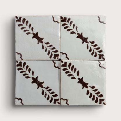Four square zellige tiles arranged in a 2x2 grid, featuring a glossy off-white glaze with a dark brown hand-painted botanical pattern of leafy stems and star-like motifs.