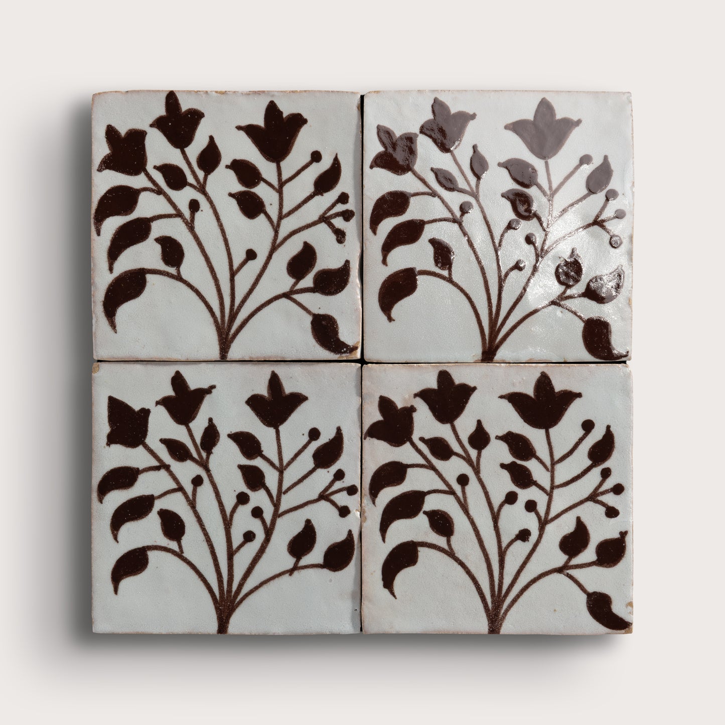four square zellige tiles in a grid format with handpainted brown pattern.