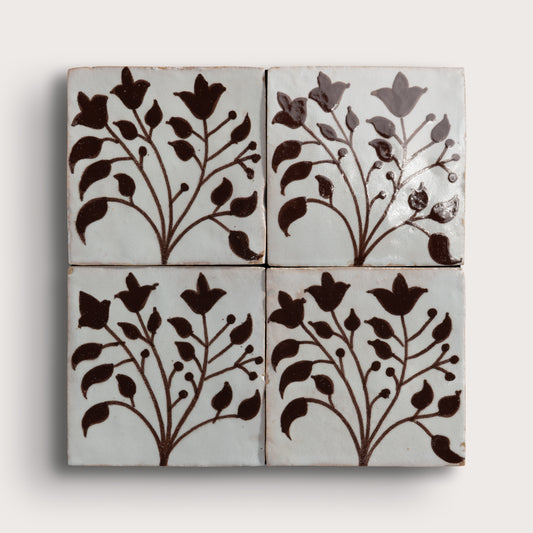 four square zellige tiles in a grid format with handpainted brown pattern.