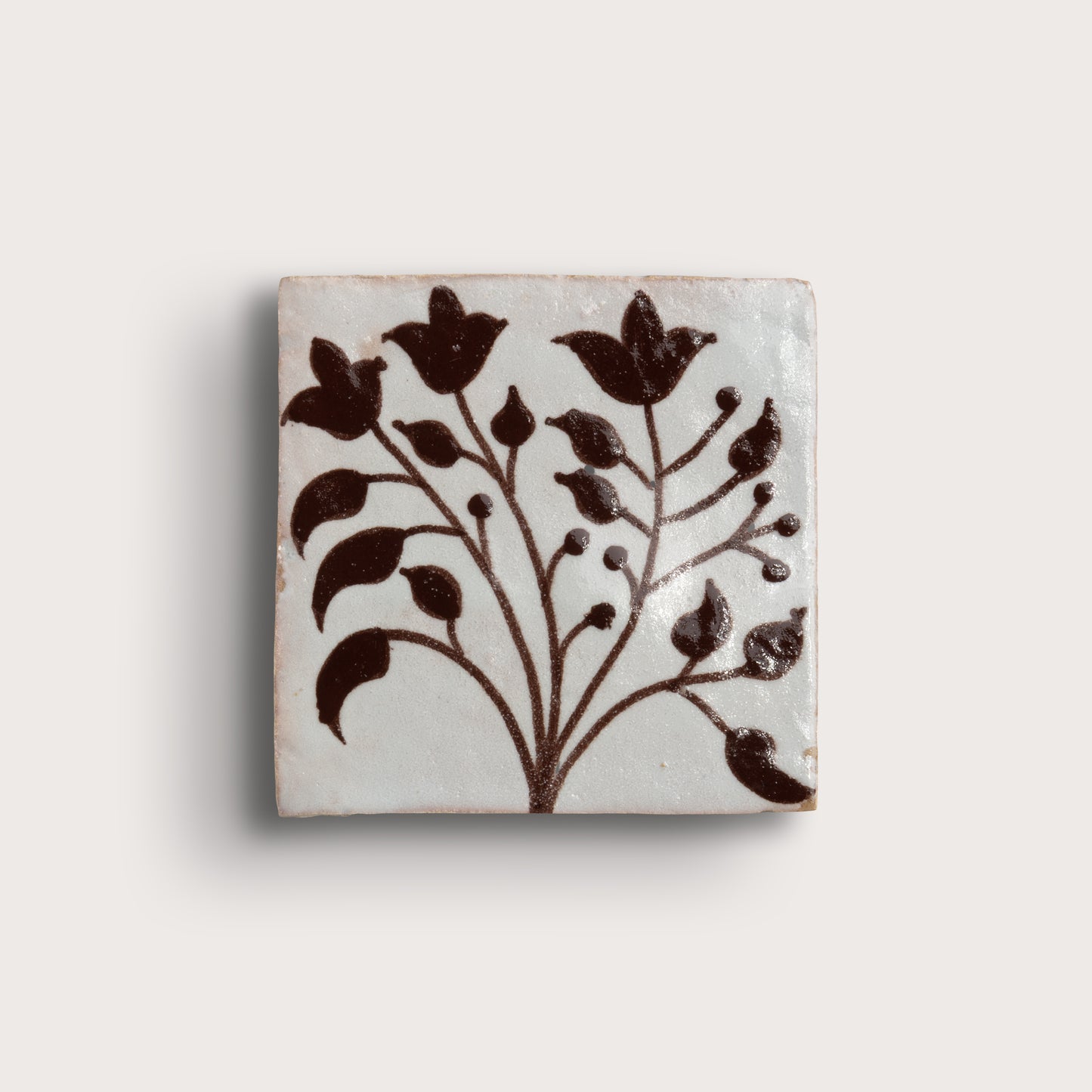 square zellige tile with handpainted brown pattern.