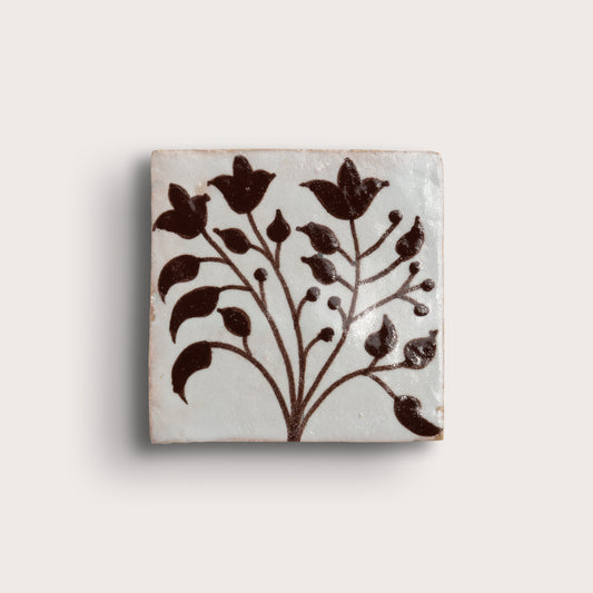 square zellige tile with handpainted brown pattern.
