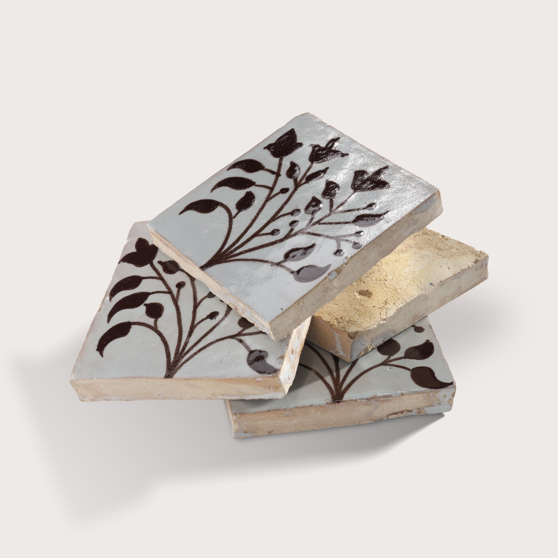 four square zellige tiles in a stacked format with handpainted brown pattern.