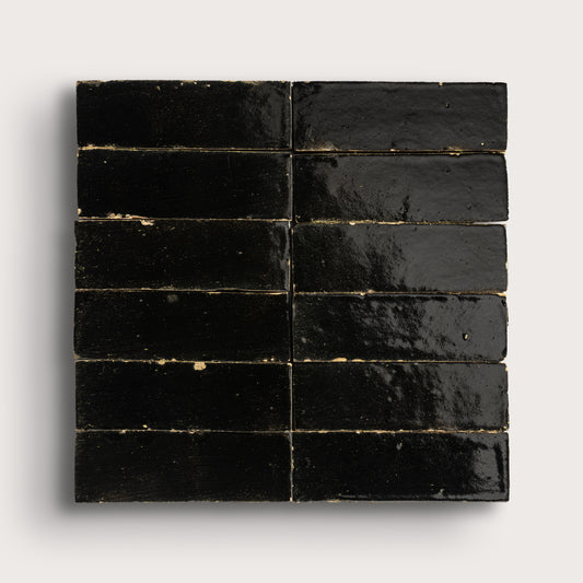 Black rectangular zellige tiles arranged in a grid pattern on a light gray background