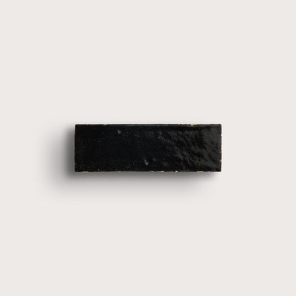 Black rectangular zellige tile on a light gray background