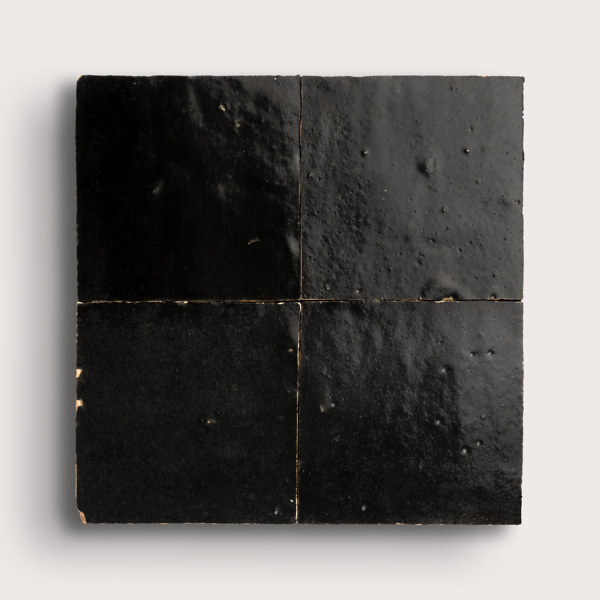 Black square zellige tiles with a textured surface on a white background