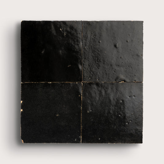 Black square zellige tiles with a textured surface on a white background