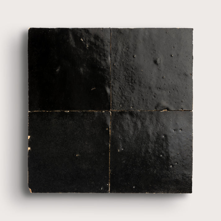 Black square zellige tiles with a textured surface on a white background