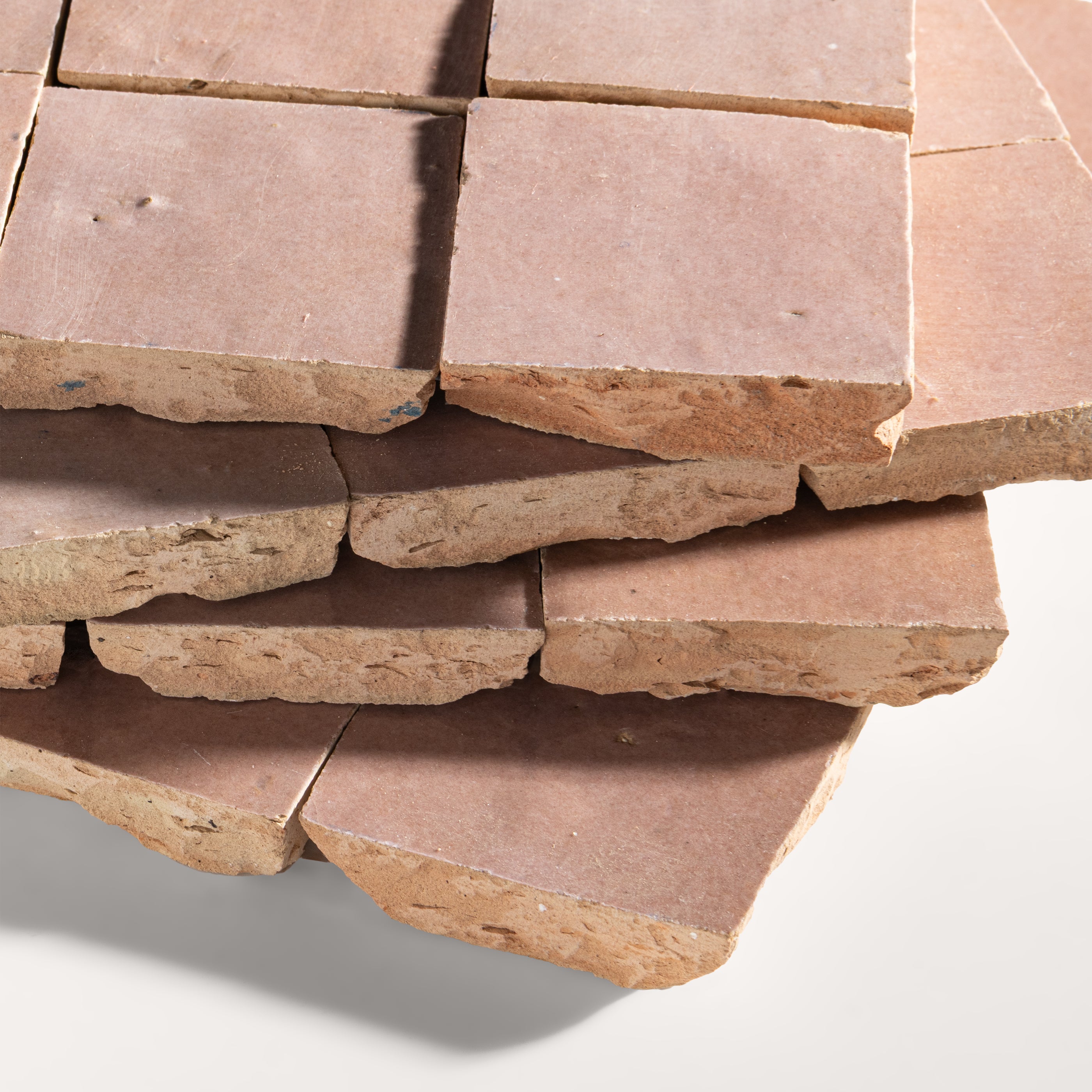 Stack of blush zellige stone tiles on a white background