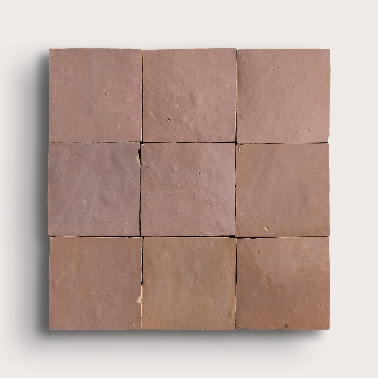 Nine zellige square tiles of a uniform blush color arranged in a 3x3 grid on a white background.