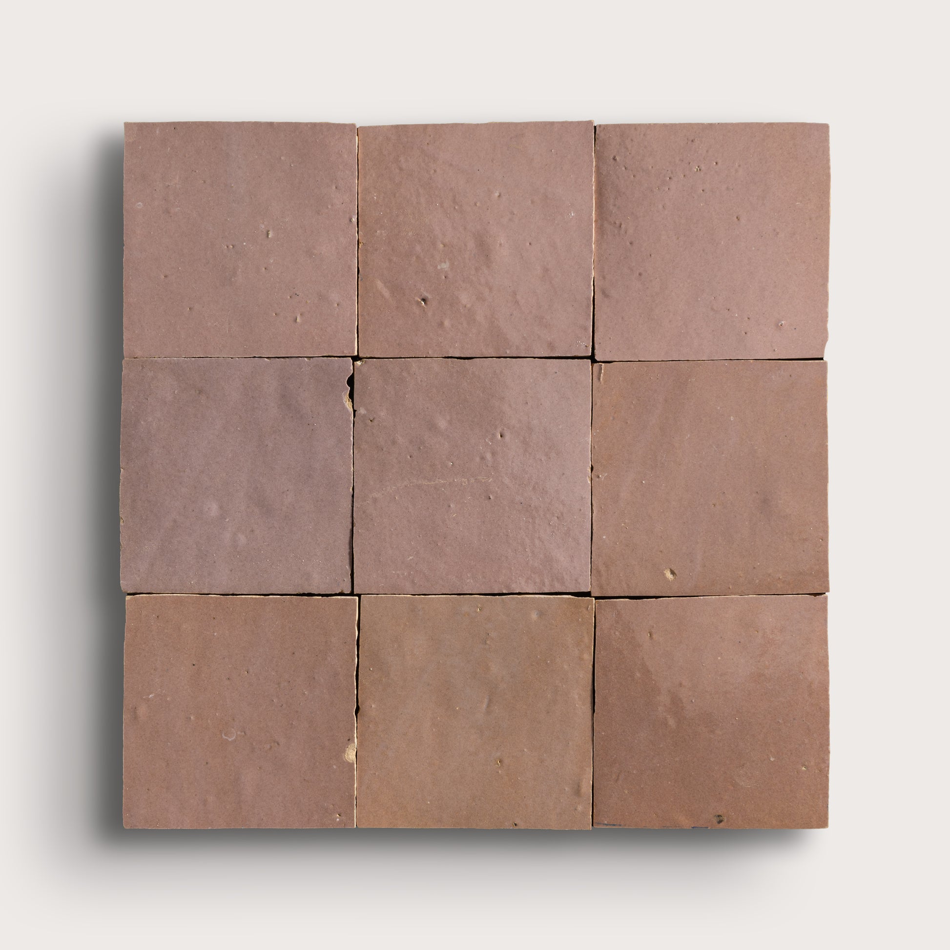 Nine zellige square tiles of a uniform blush color arranged in a 3x3 grid on a white background.
