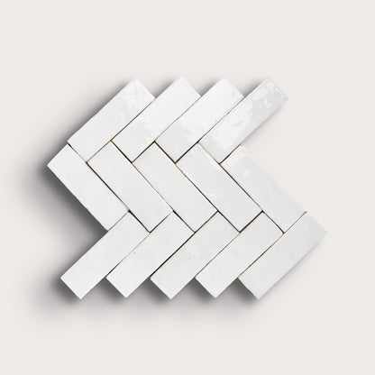 White herringbone mosaic tile pattern on a light gray background