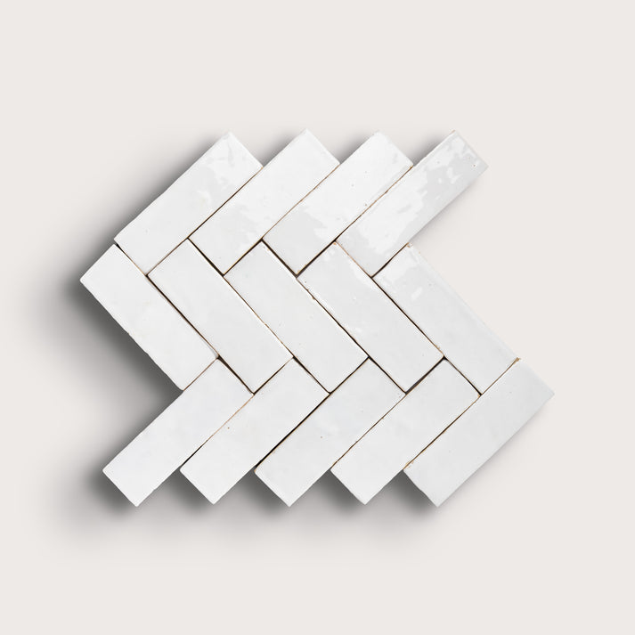 White herringbone mosaic tile pattern on a light gray background