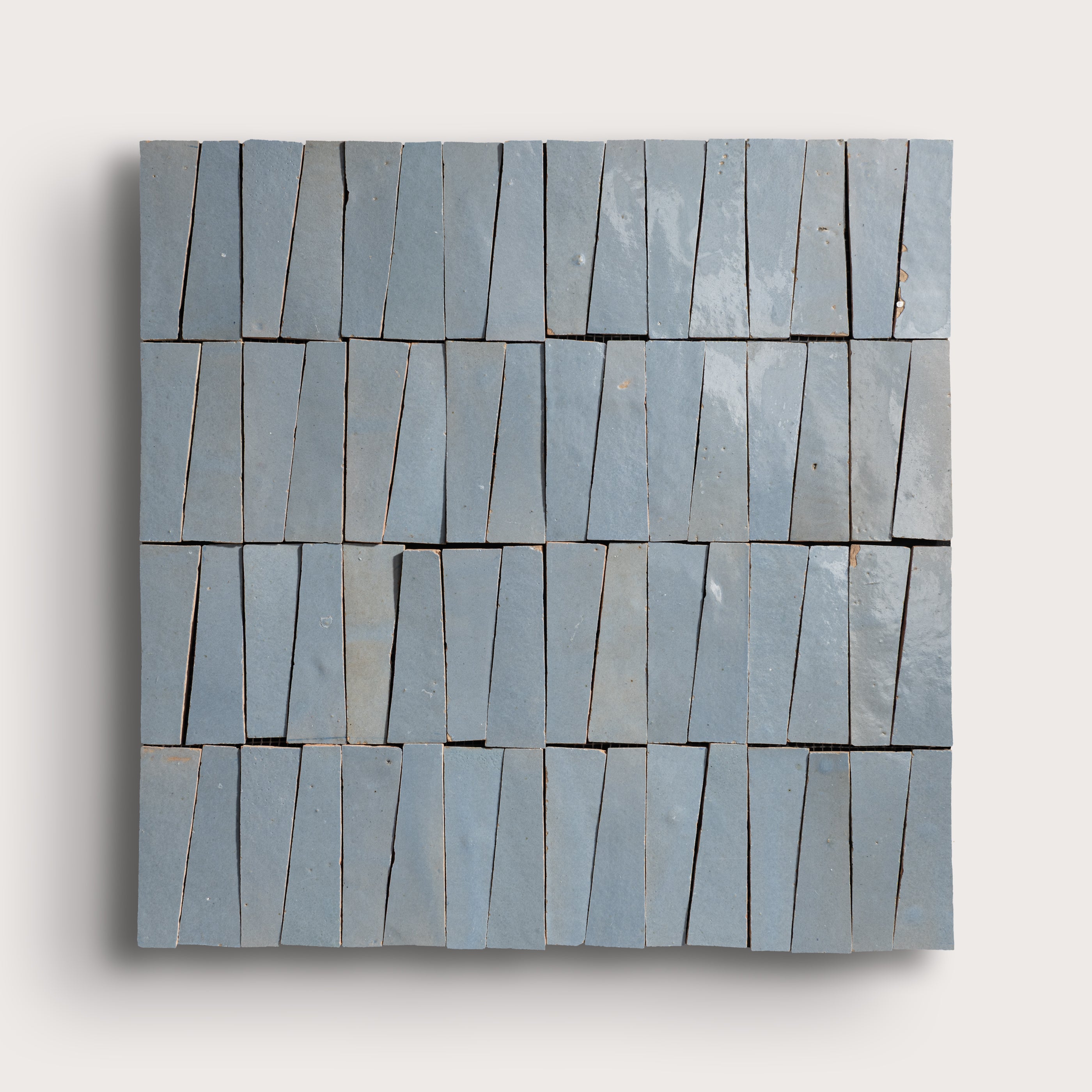 Rectangular blue zellige tile with a geometric pattern on a light gray background
