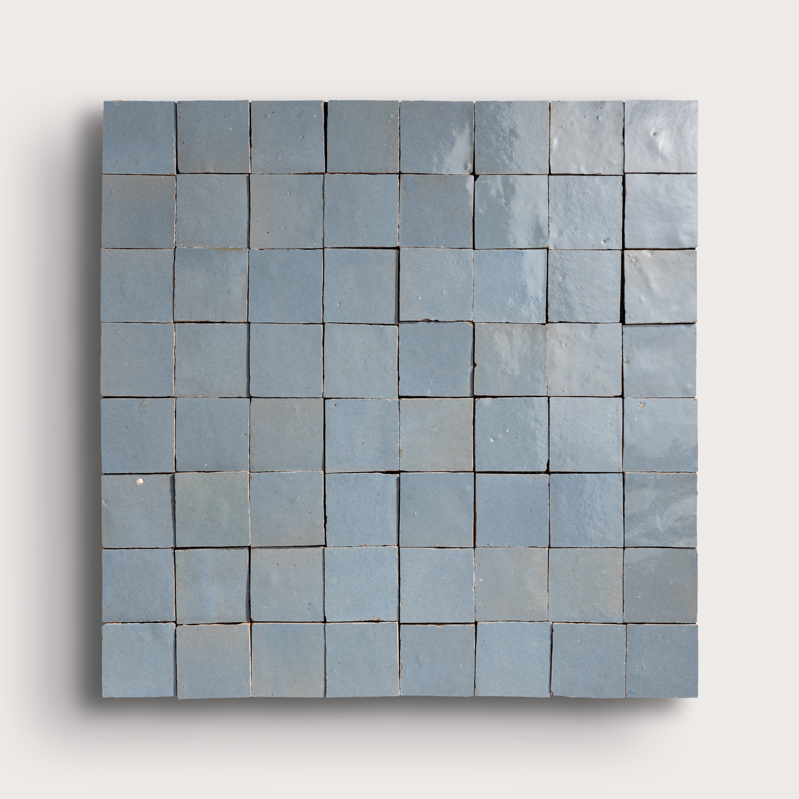 Blue square zellige tile with a grid of smaller tiles on a light gray background