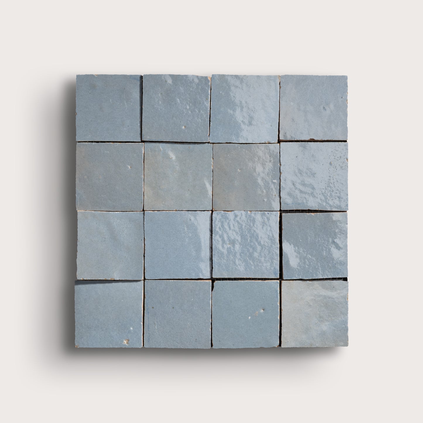Blue square zellige tile with a grid of smaller tiles on a light gray background