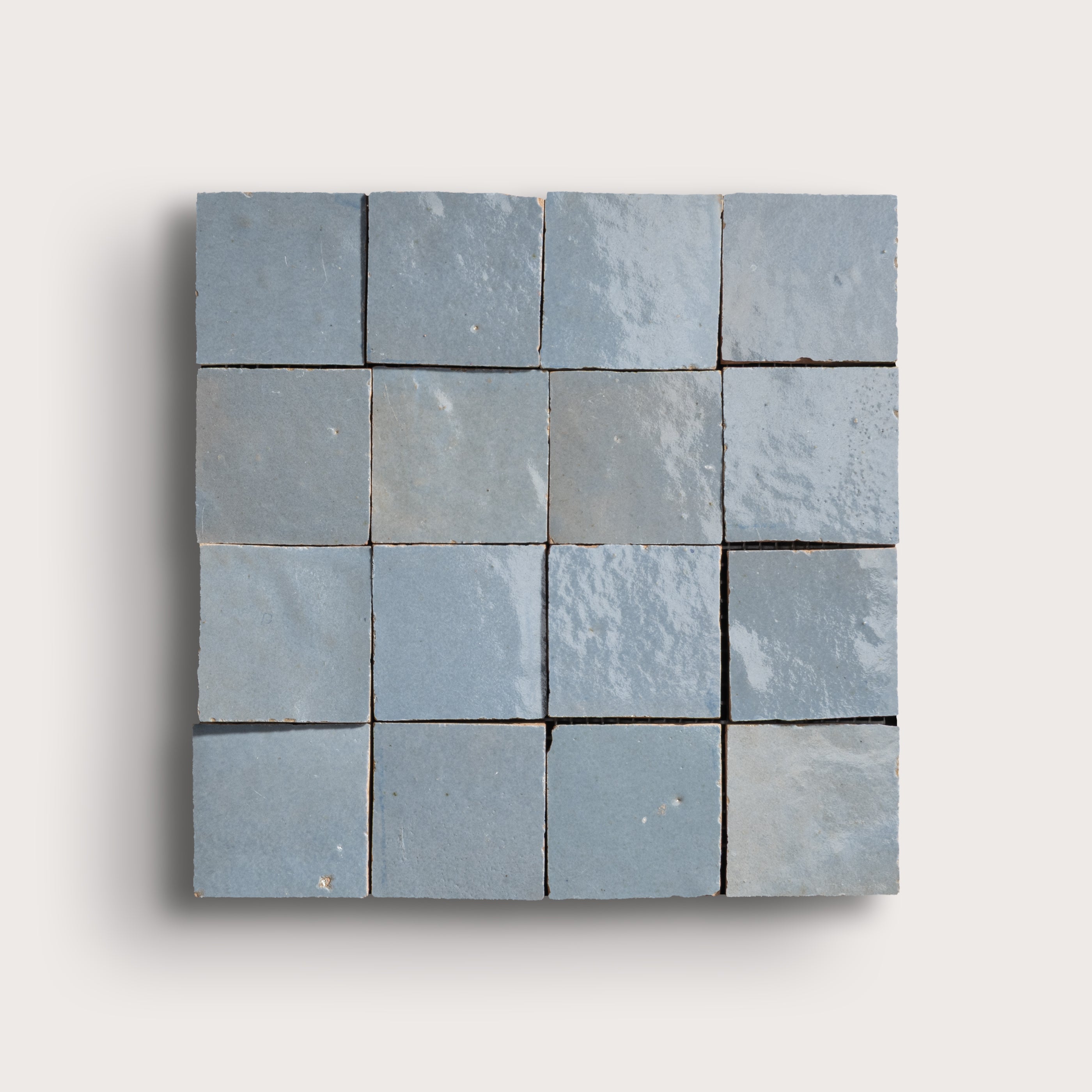 Blue square zellige tile with a grid of smaller tiles on a light gray background