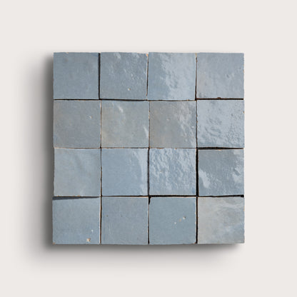Blue square zellige tile with a grid of smaller tiles on a light gray background