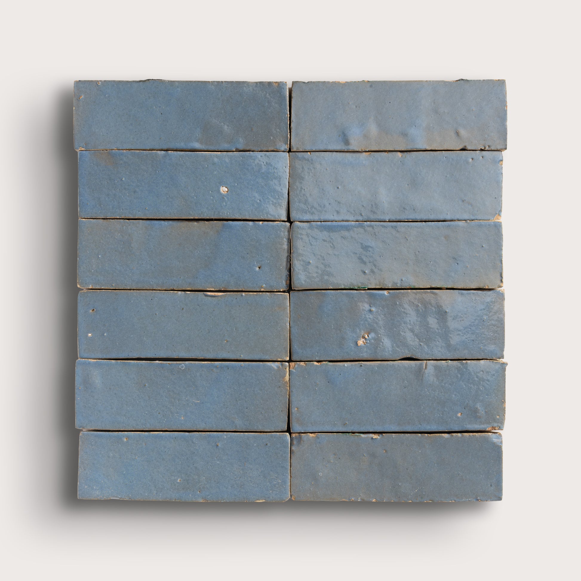 twelve blue rectangular zellige tiles arranged in a grid on a white background