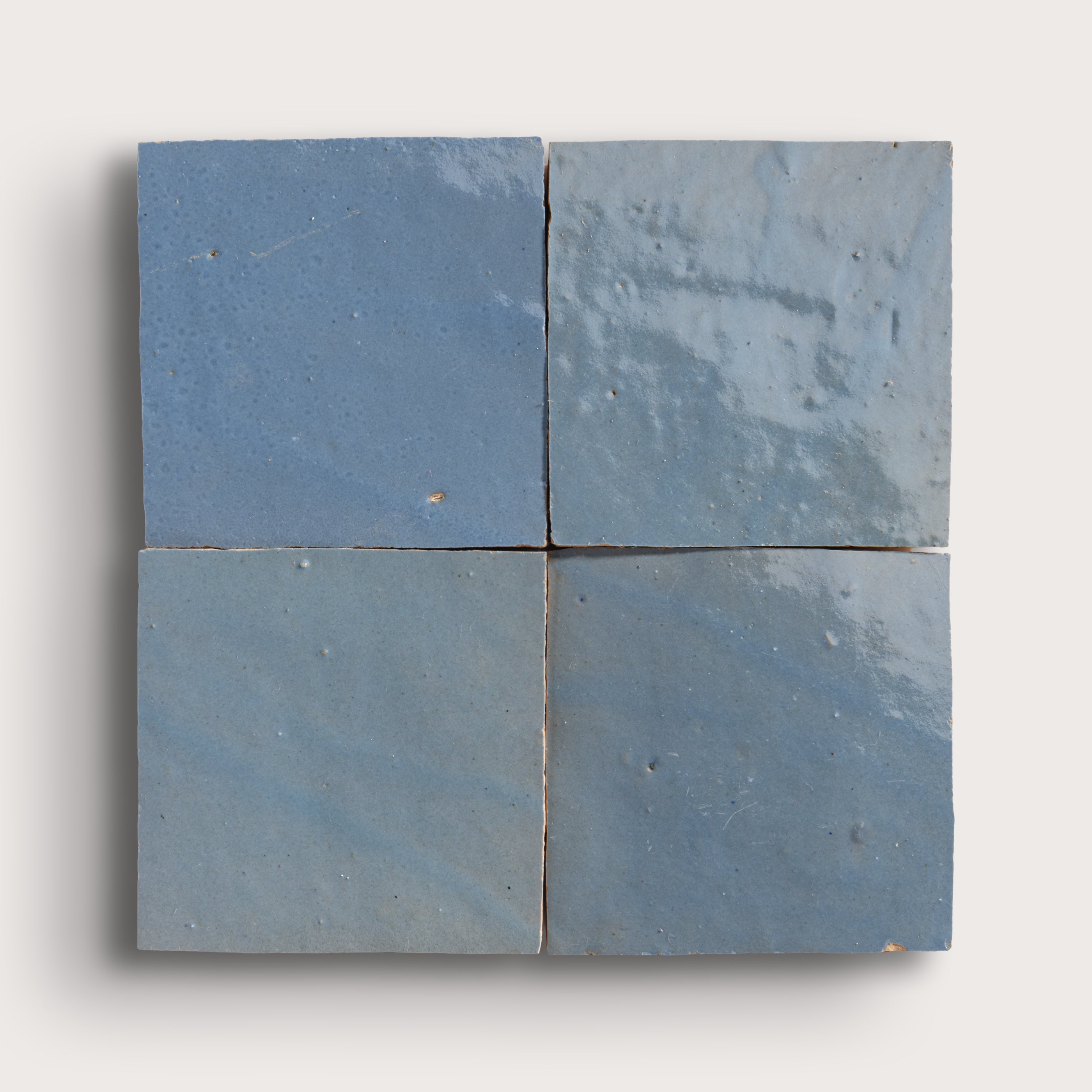 Four blue square zellige tiles on a white background
