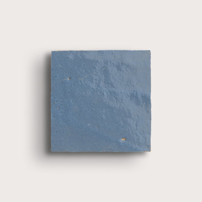 Blue square zellige tile on a light gray background