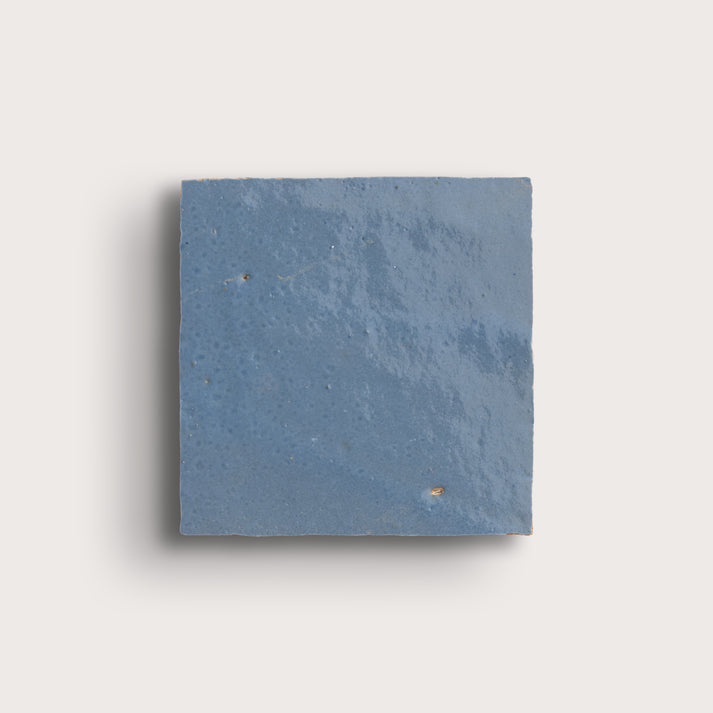 Blue square zellige tile on a light gray background