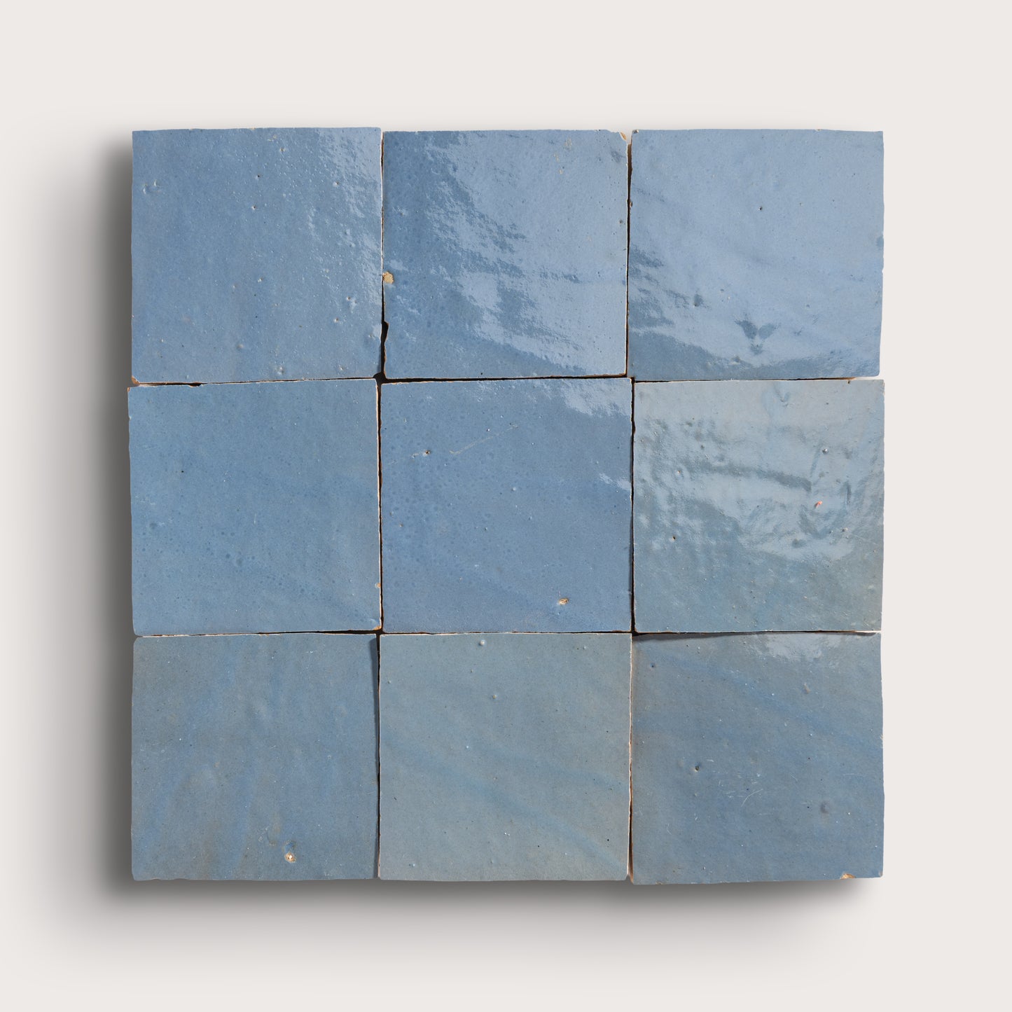Nine blue square zellige tiles arranged in a 3x3 grid on a white background