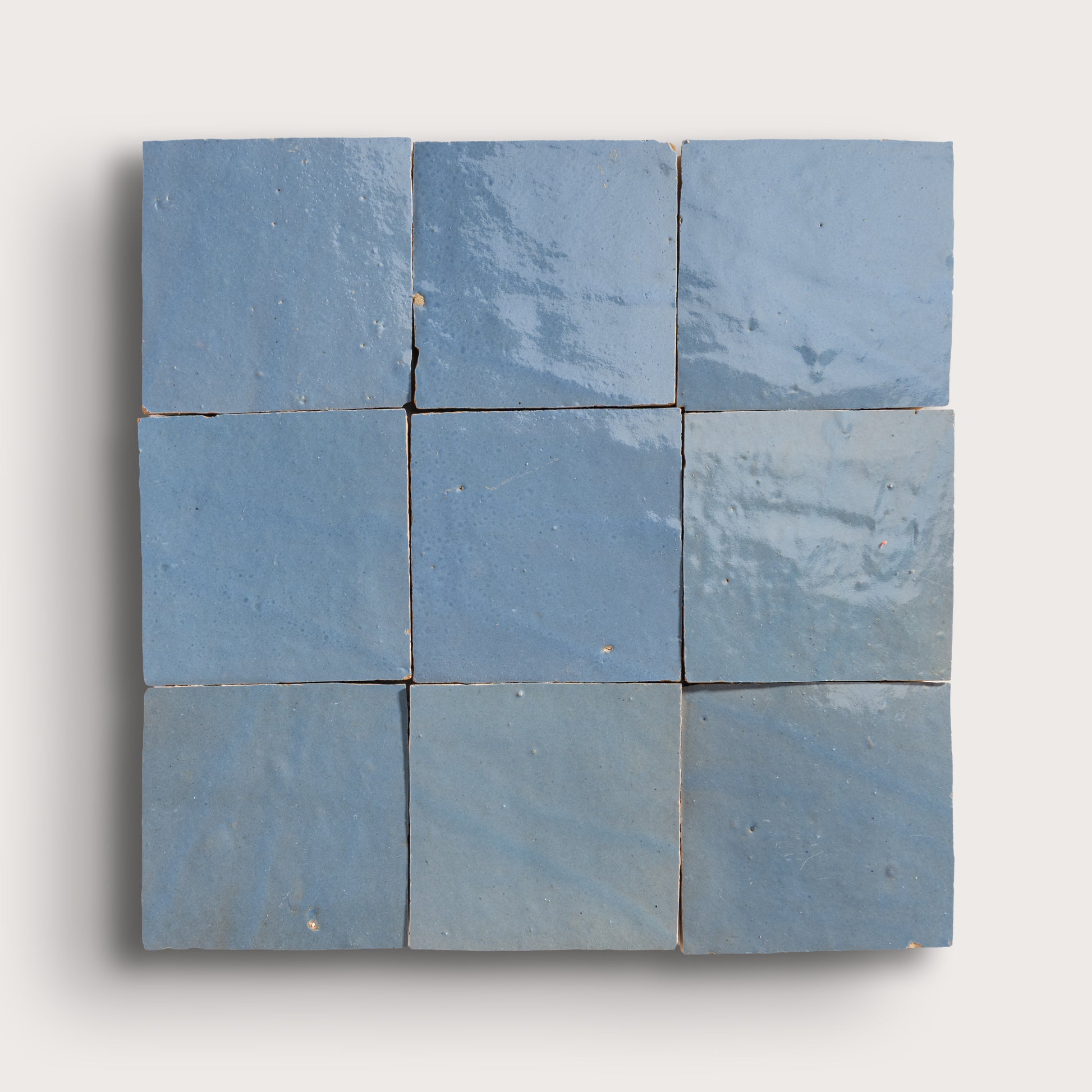 Nine blue square zellige tiles arranged in a 3x3 grid on a white background