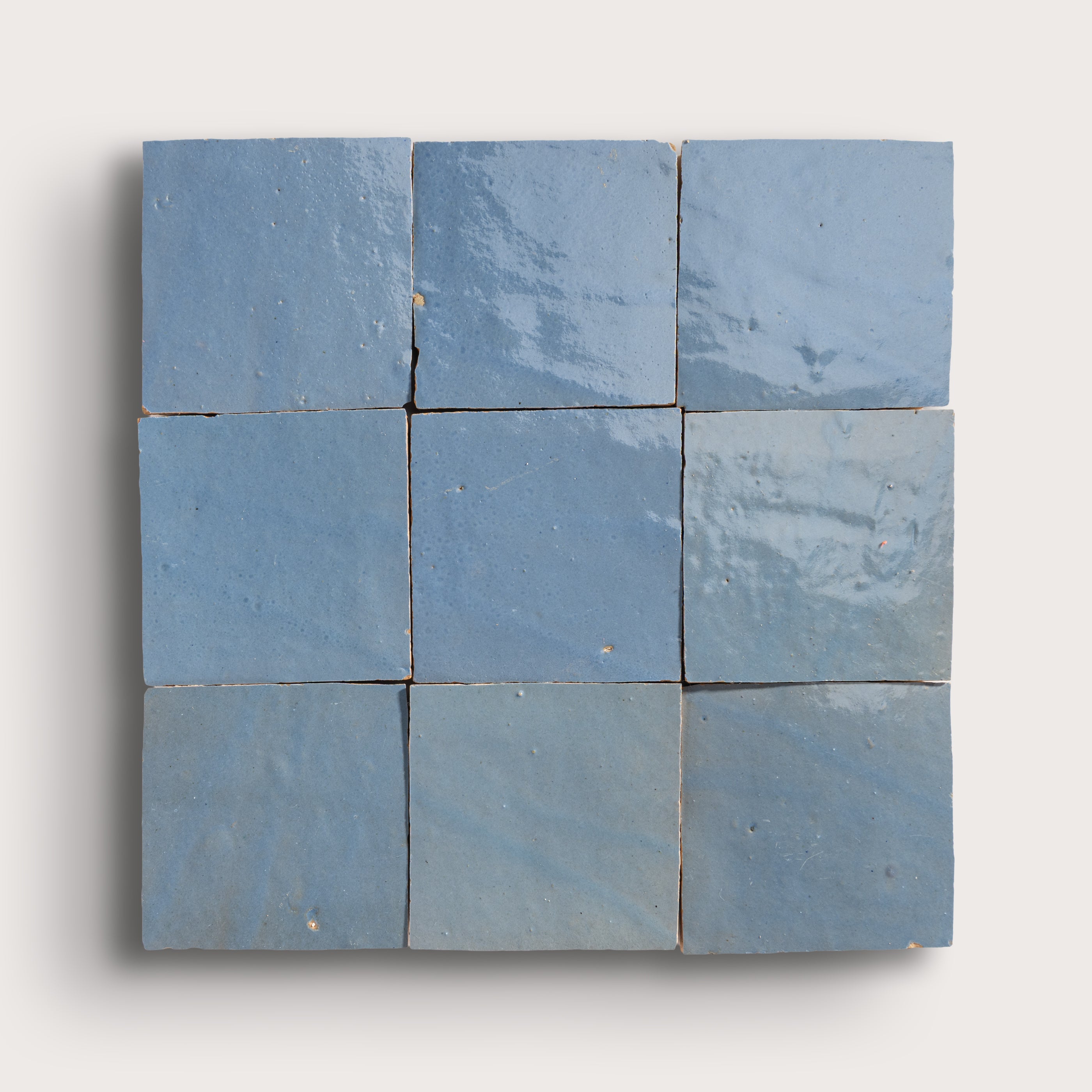 Nine blue square zellige tiles arranged in a 3x3 grid on a white background
