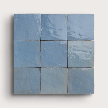 Nine blue square zellige tiles arranged in a 3x3 grid on a white background