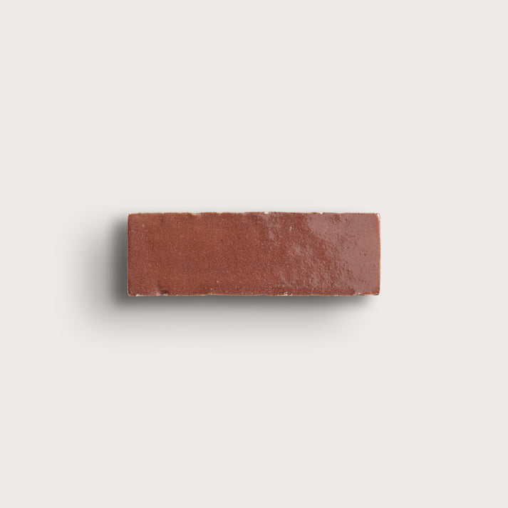 Rectangular red zellige tile on a light gray background