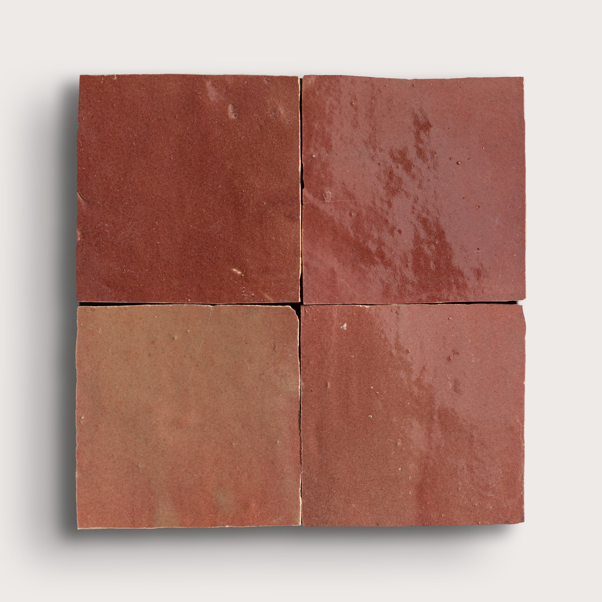 Four square zellige tiles with a red-brown color pattern on a white background