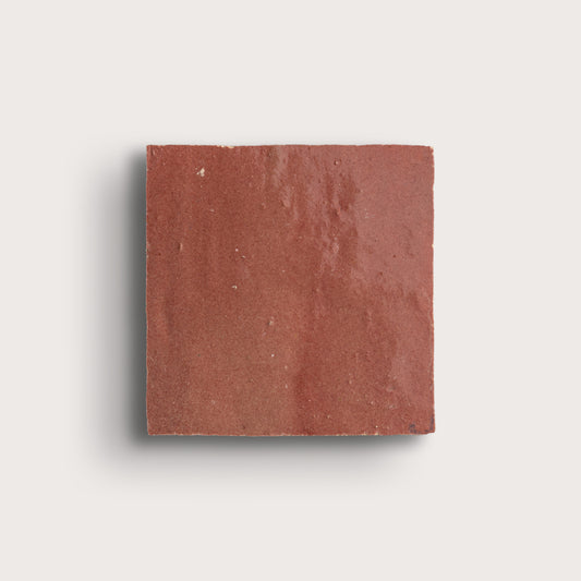 Square red zellige tile on a light gray background