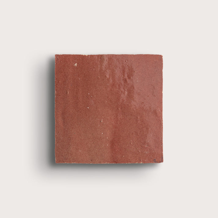 Square red zellige tile on a light gray background