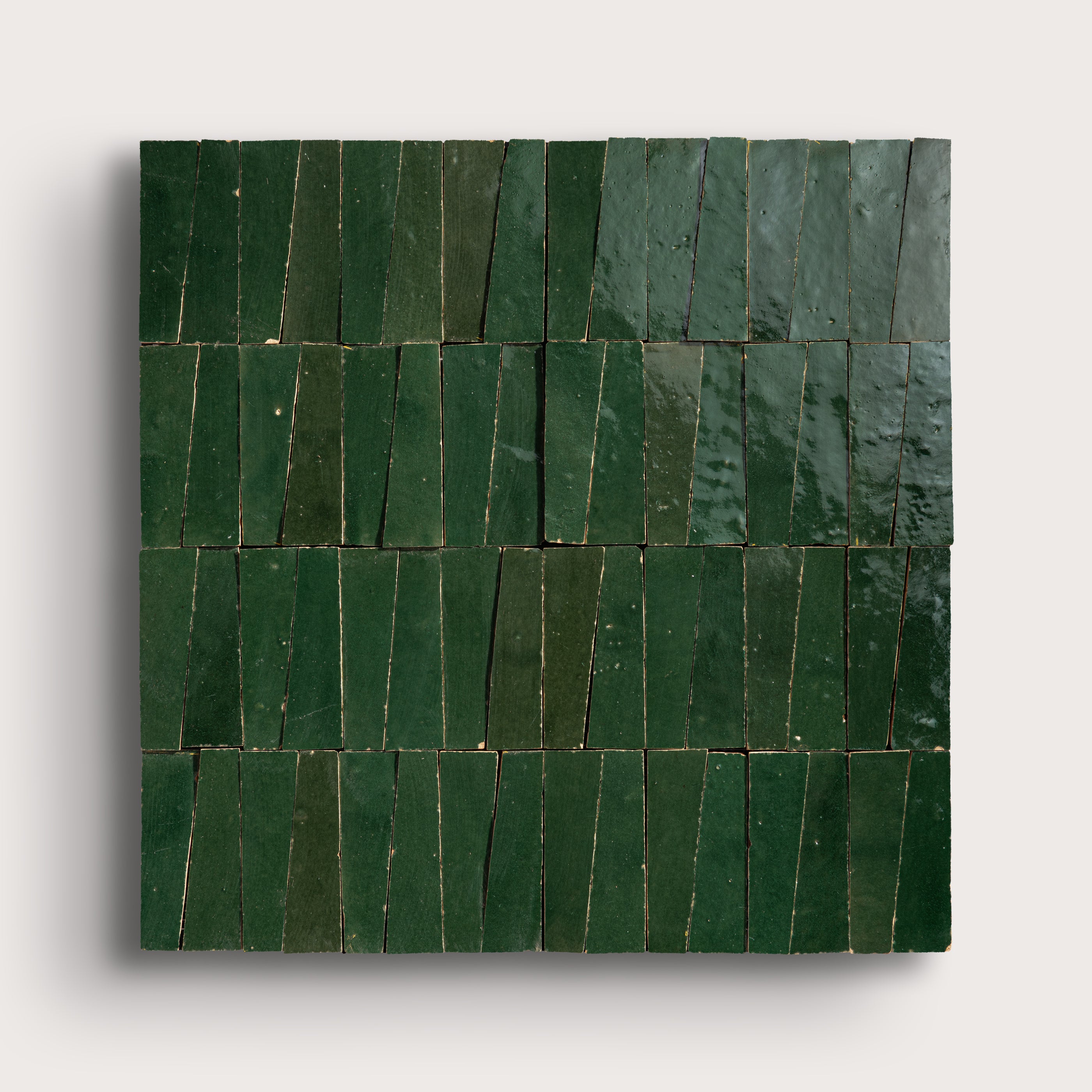 Green zellige trapezoid tiles arranged in a pattern on a light gray background