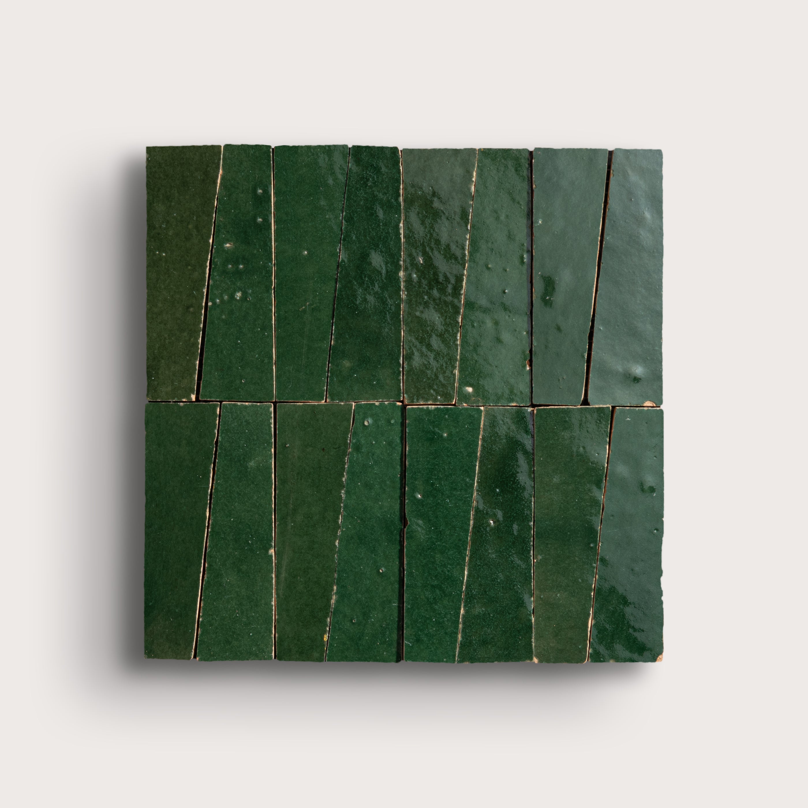 Green zellige trapezoid tiles arranged in a pattern on a light gray background
