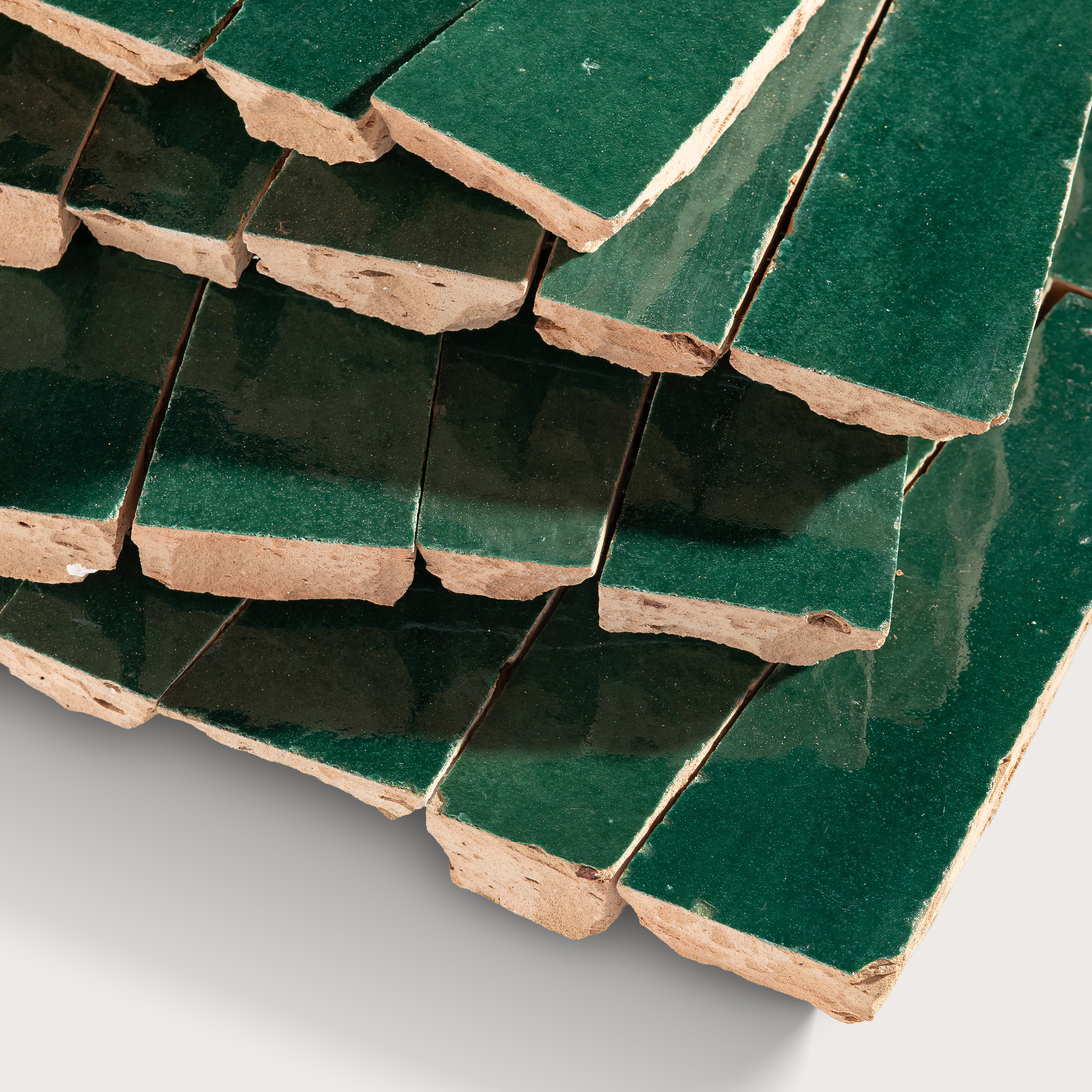 Stack of green zellige tiles on a white background