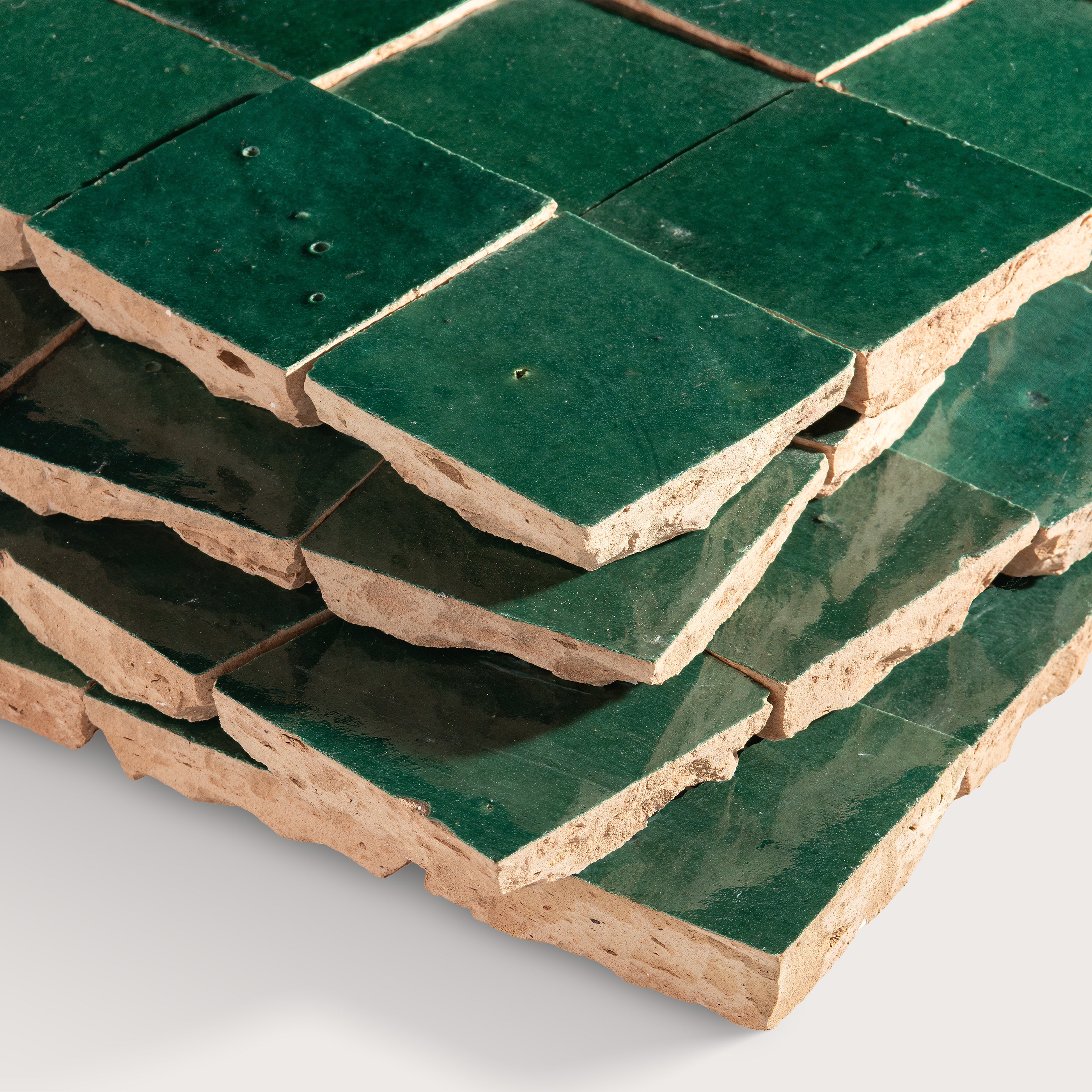 Stack of green zellige tiles on a white background