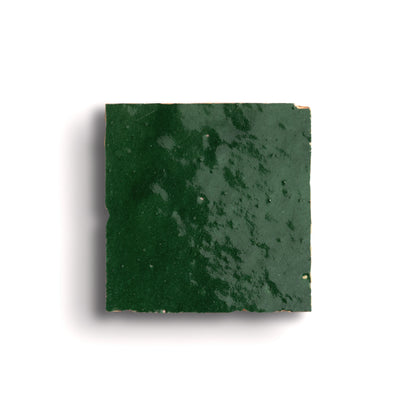 Square piece of green zellige tile on a white background