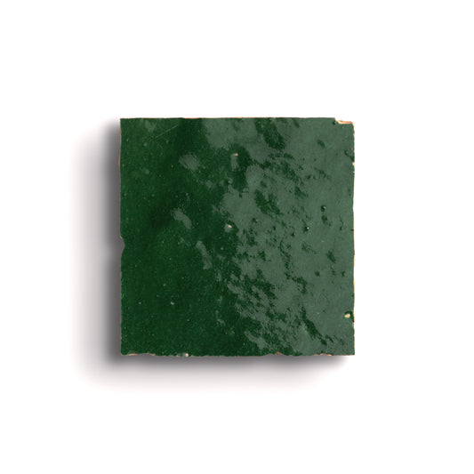 Square piece of green zellige tile on a white background