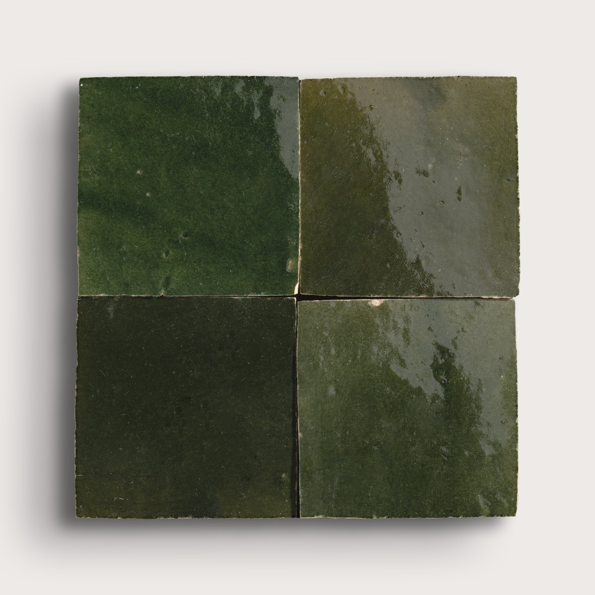Four square green zellige tiles on a white background