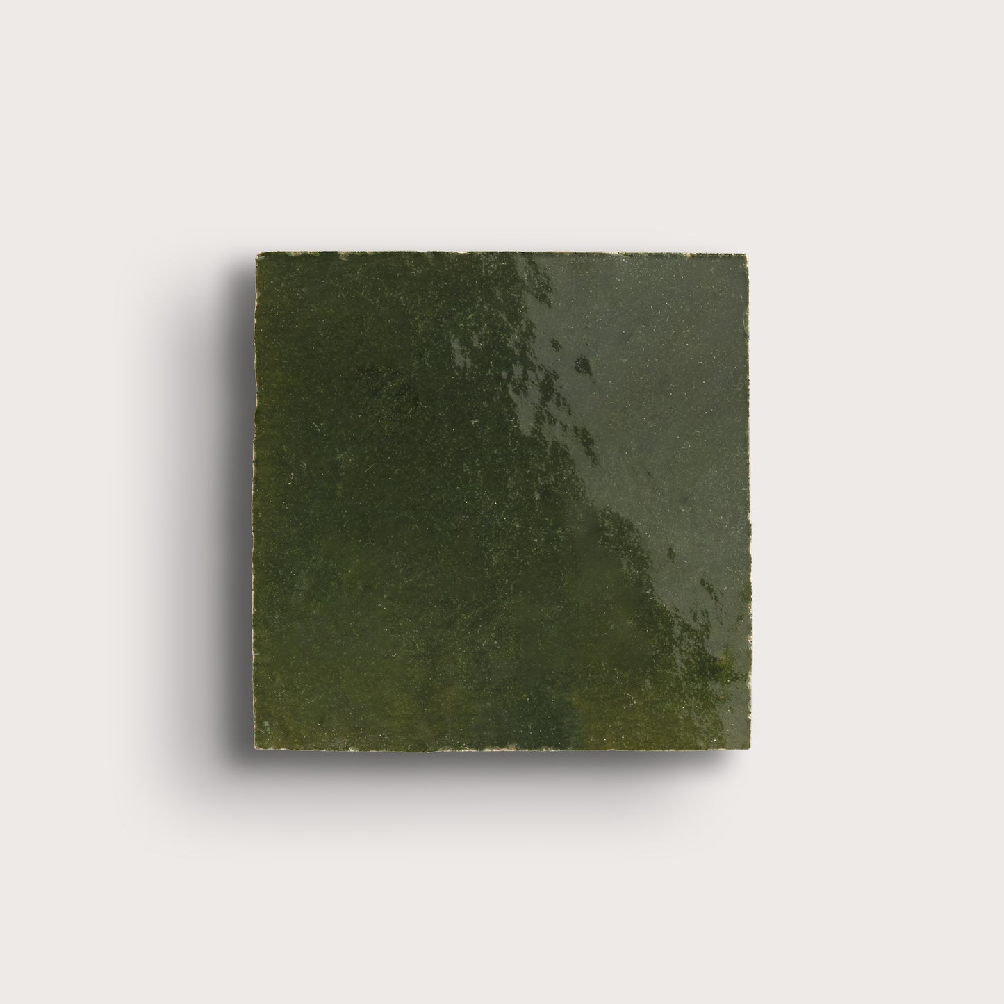 Square piece of green zellige tile on a light gray background