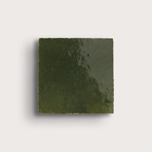 Square piece of green zellige tile on a light gray background