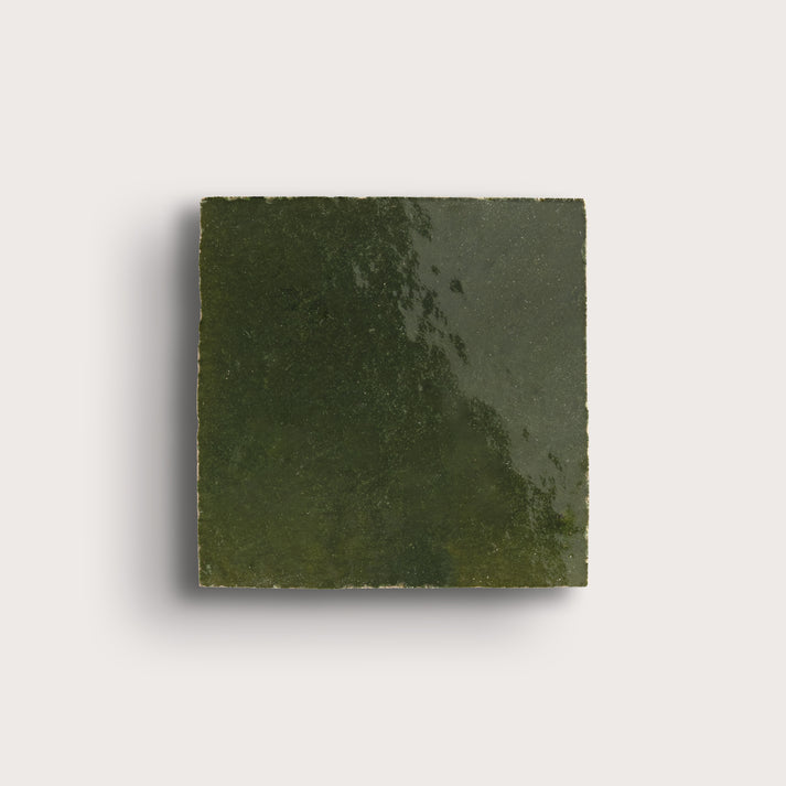 Square piece of green zellige tile on a light gray background